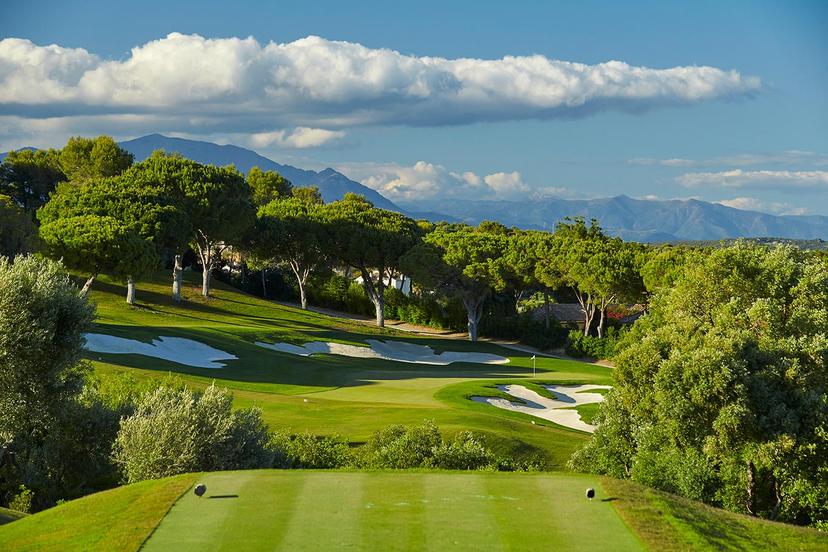 View from a tee box to a Par 3 green surrounded by bunkers