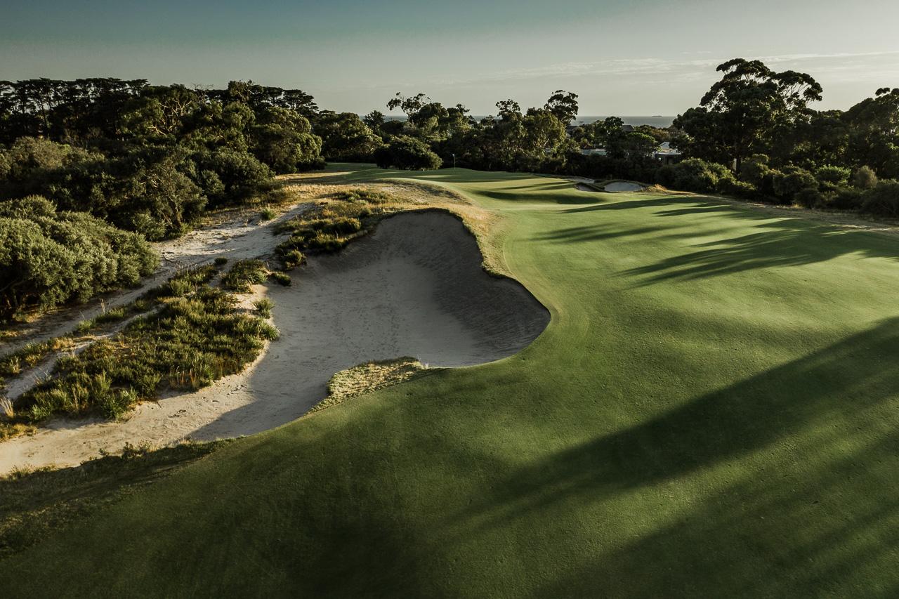 A well maintained fairway leading to a smooth green surrounded by forest trees