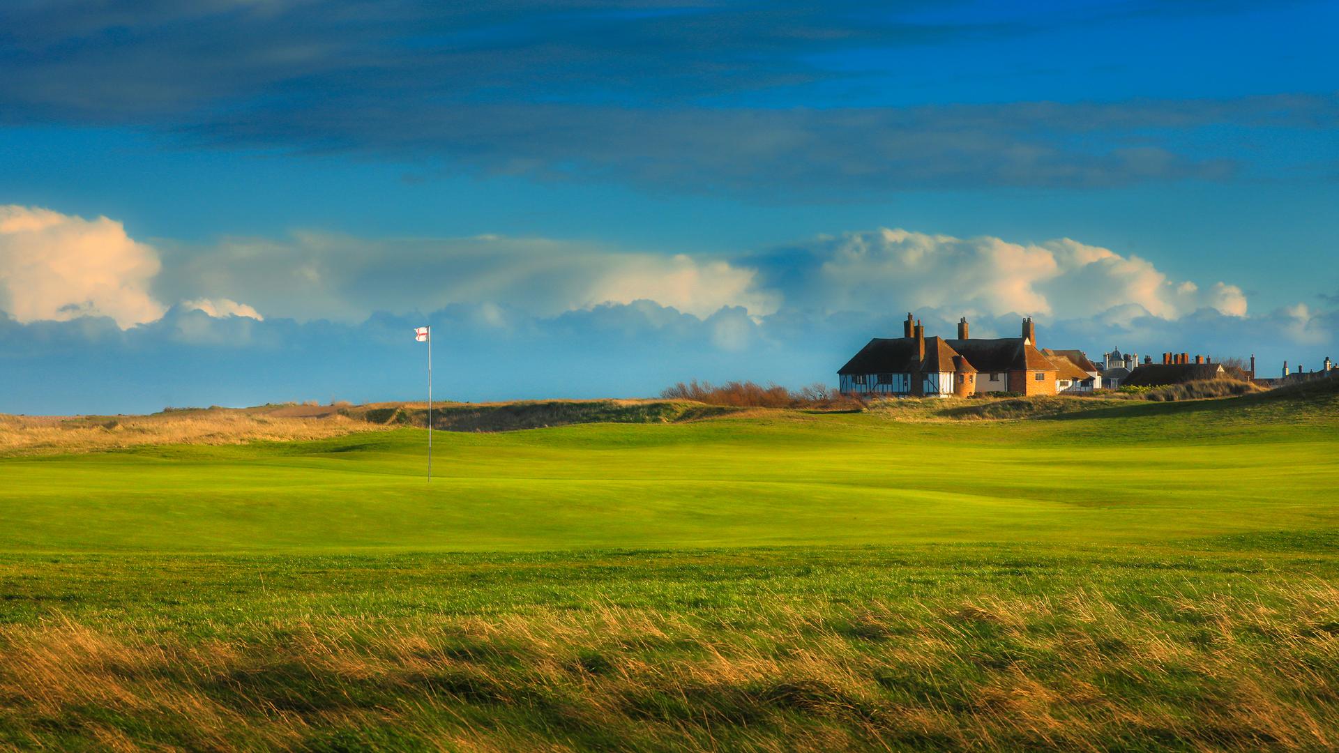 Royal St George's clubhouse looking over manicured greens at with an English flagstick