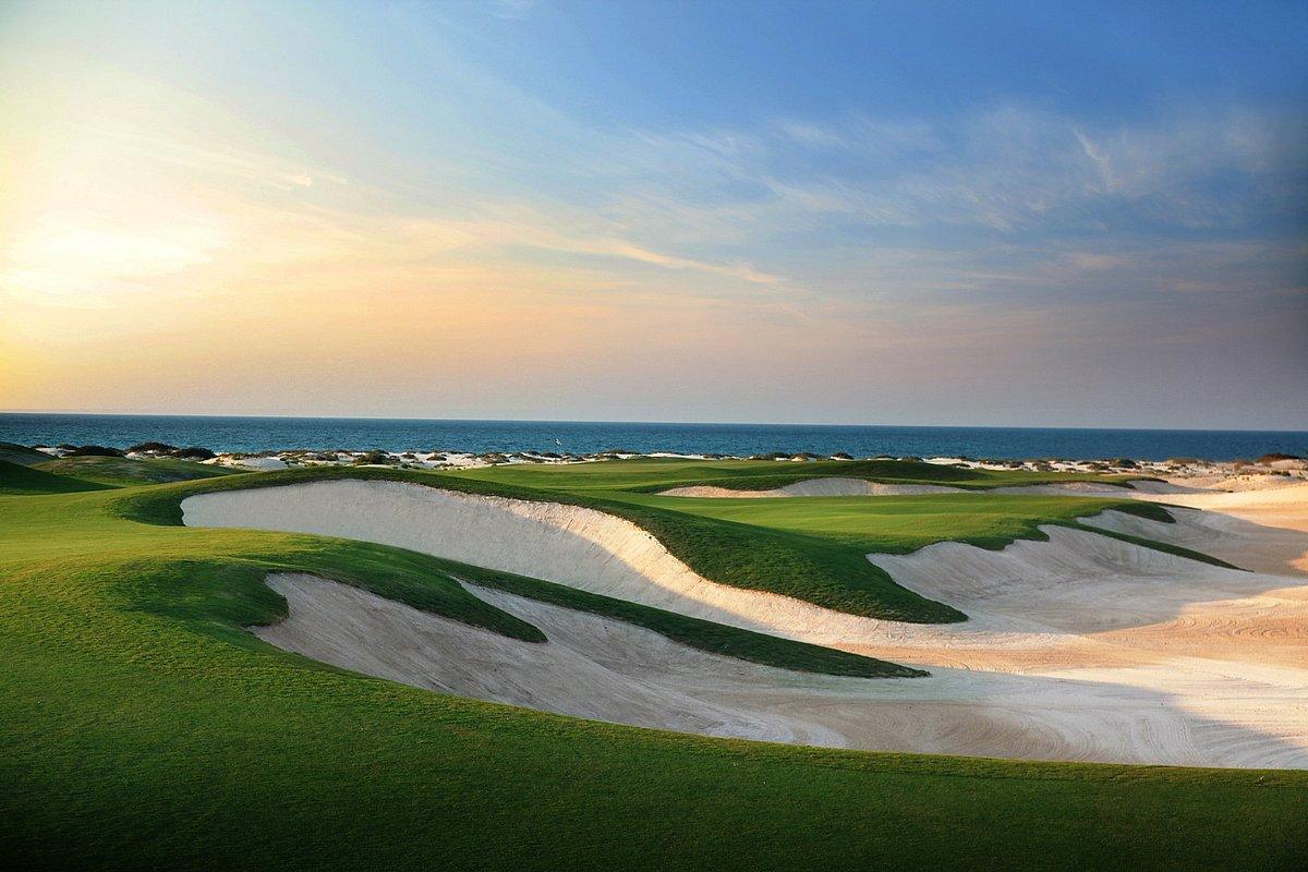 A winding fairway nestled with large sand bunkers leading to a smooth green