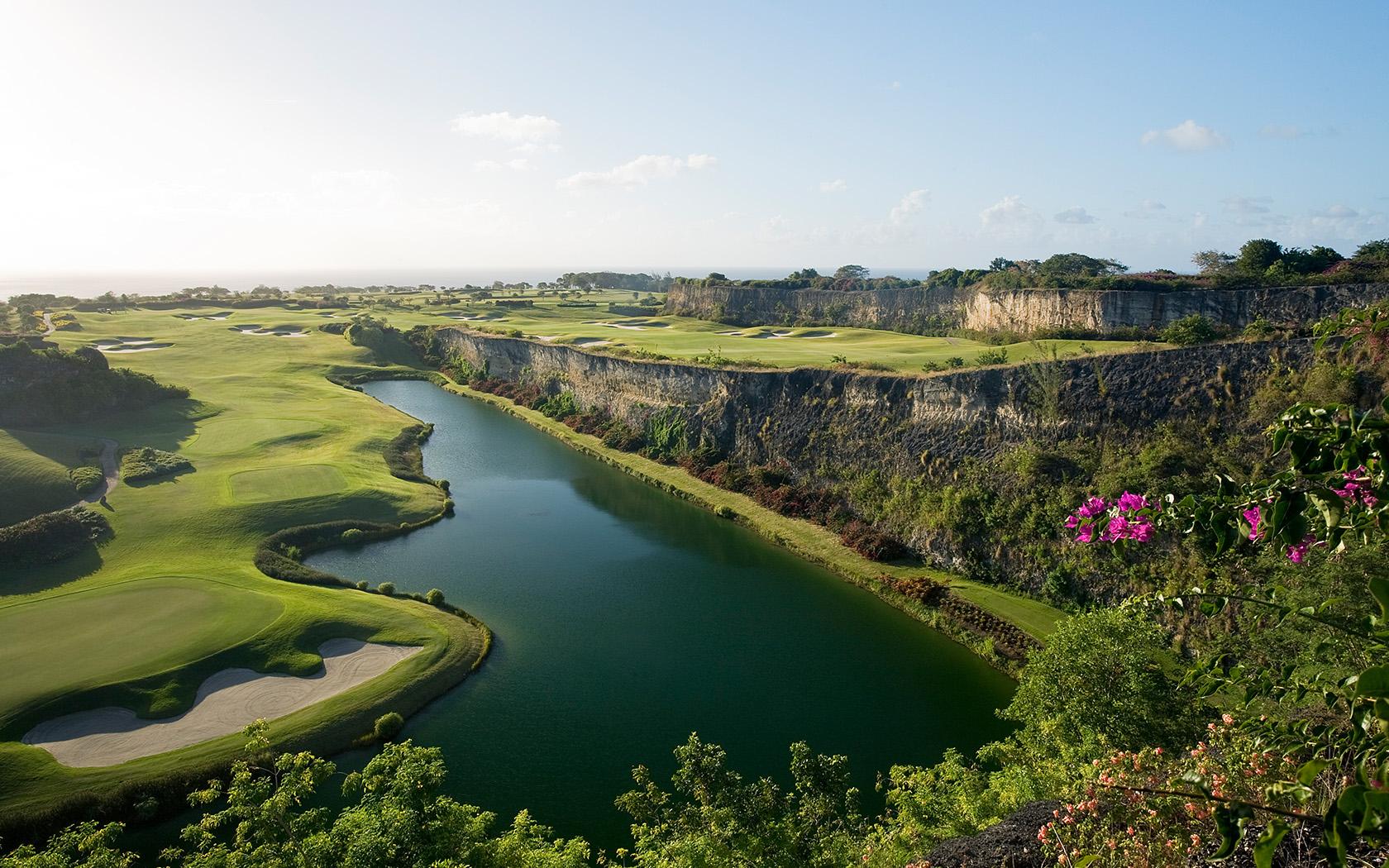 Elevated perspective of the lush green course bordered by natural cliffs, offering panoramic views of the ocean and surrounding vegetation.