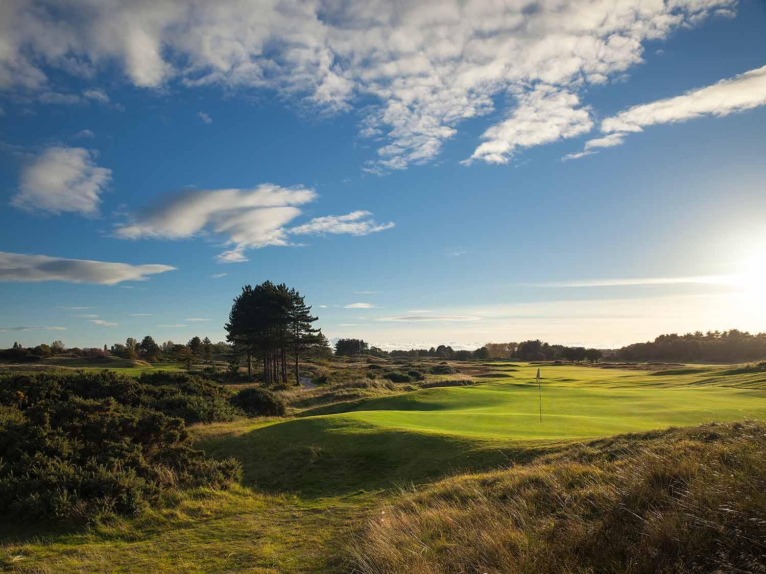 Sun shining down on the smooth green at the course under blue skies
