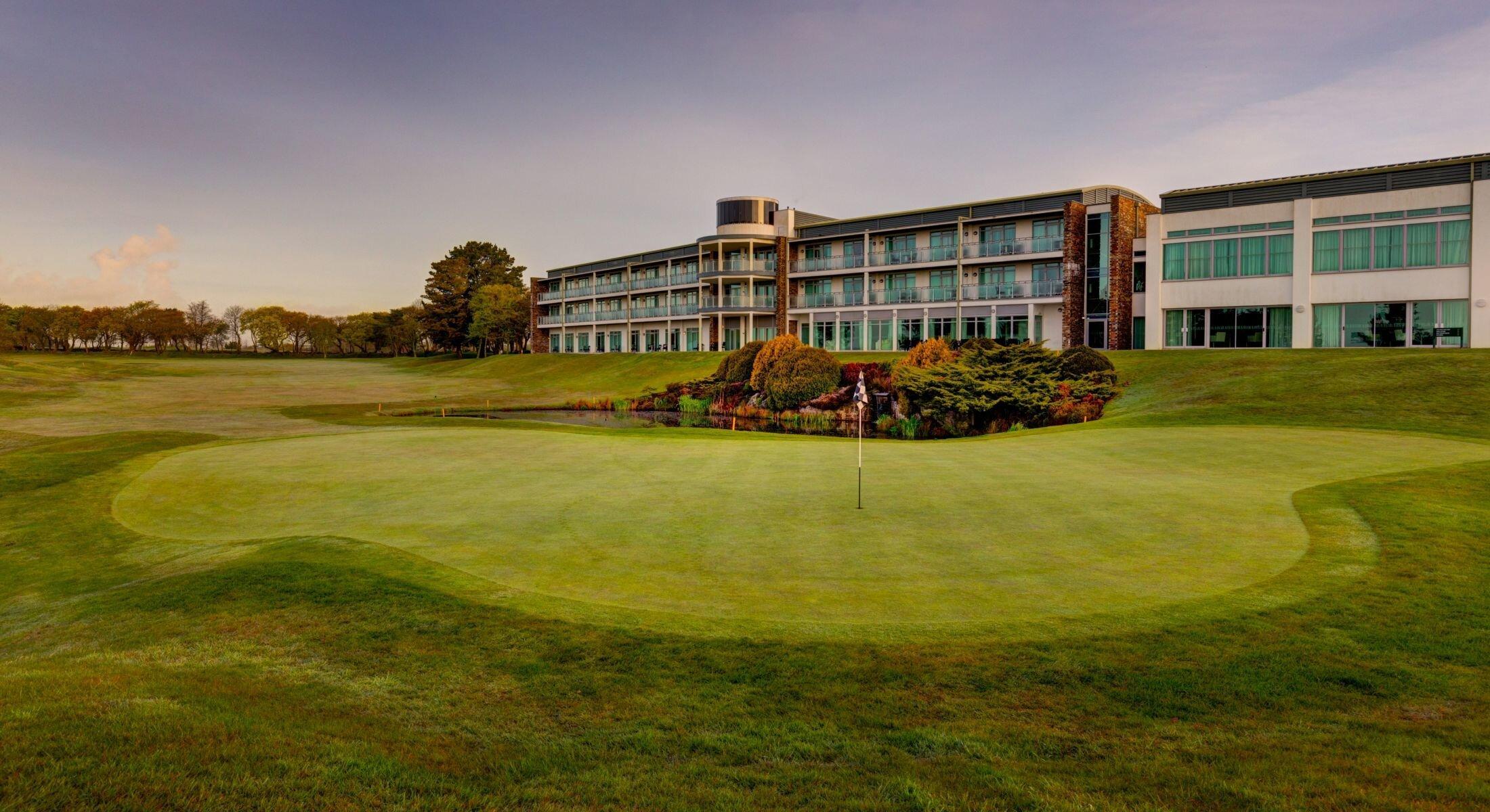 The St Mellion Estate clubhouse overlooking water hazard placed next to smooth green