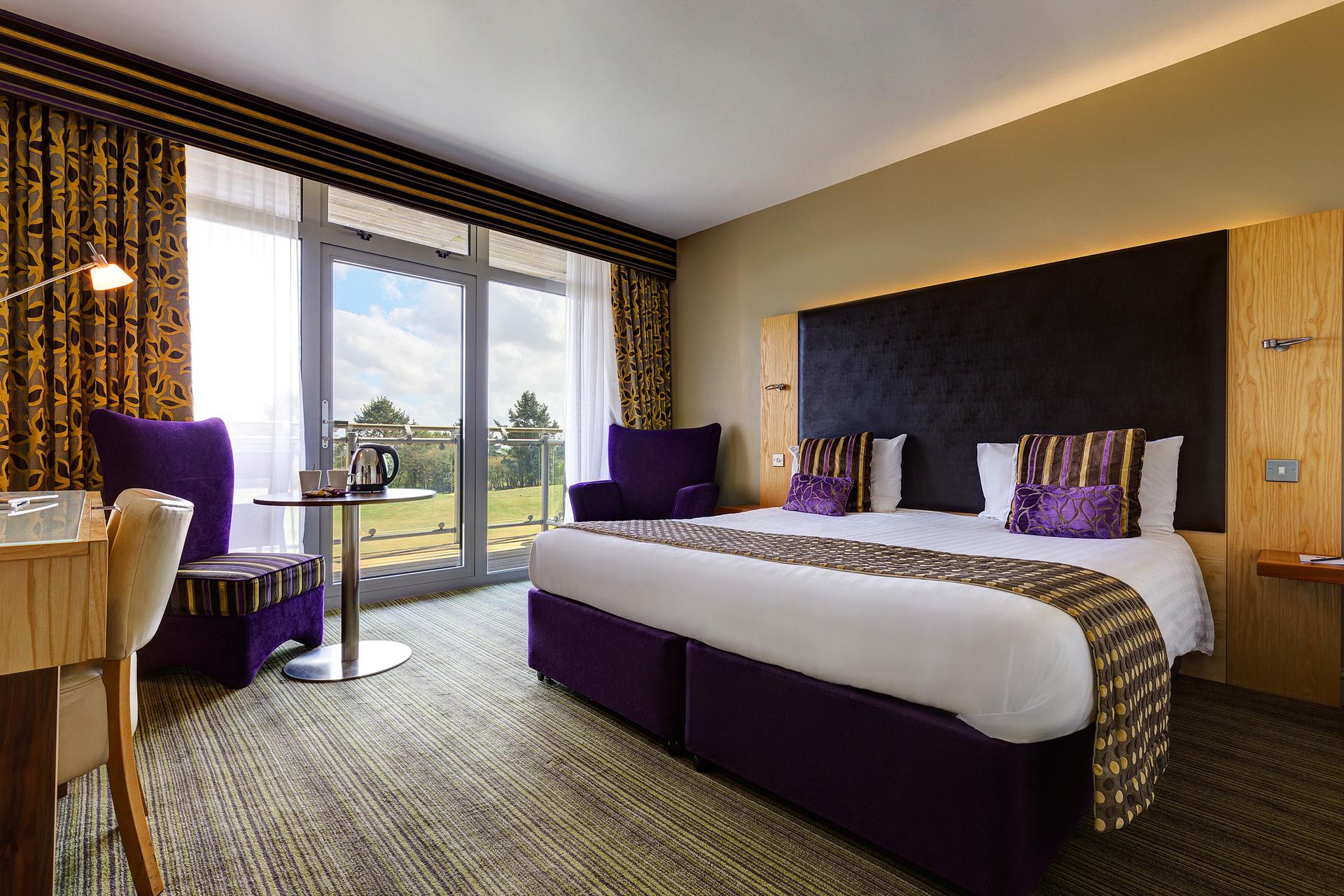 Double bet suite at the St. Mellion Estate hotel following a purple theme with a patio for lovely views of the course