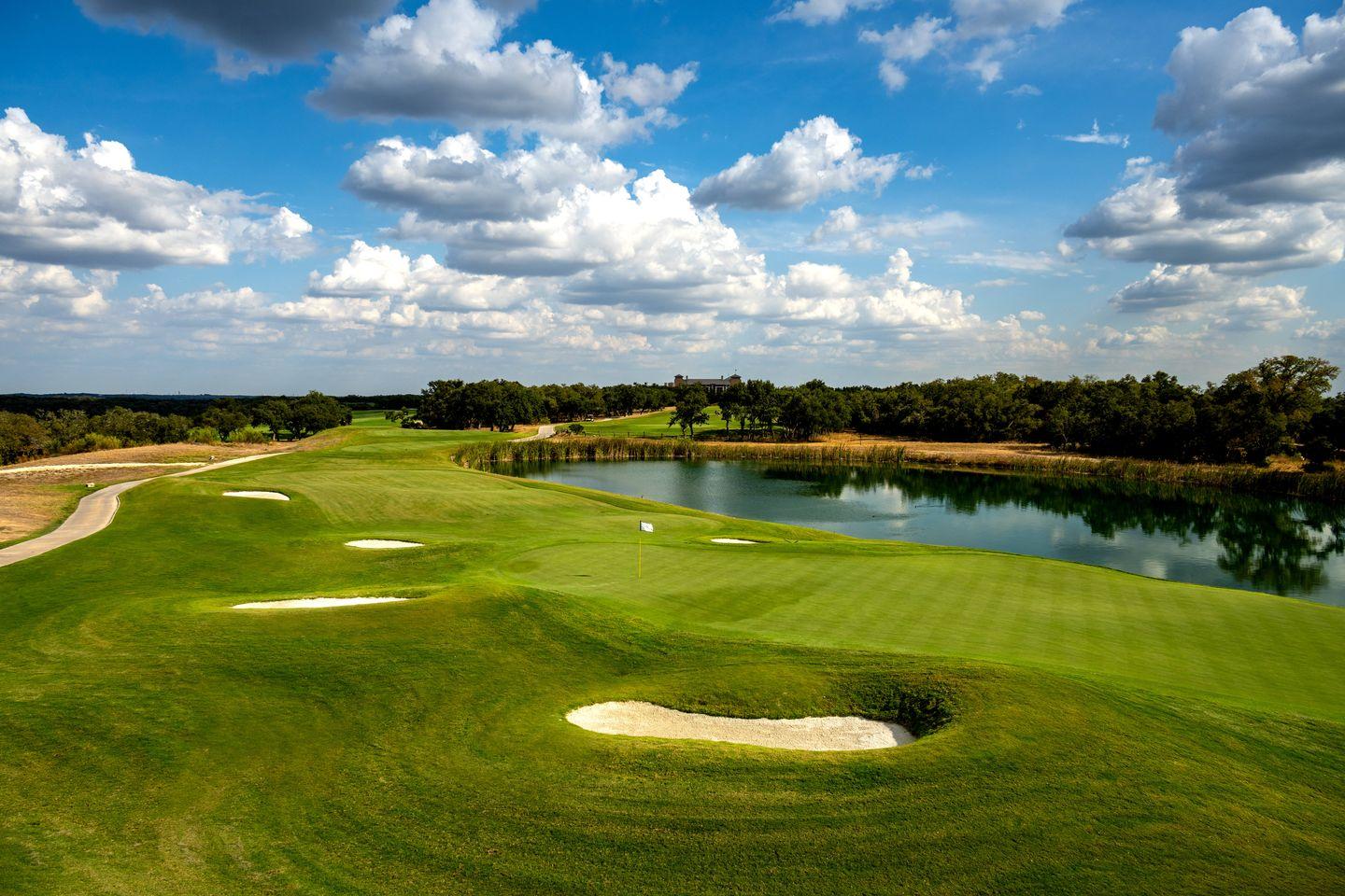 Lakeside golf hole with pristine fairways reflecting under dramatic Texas skies.