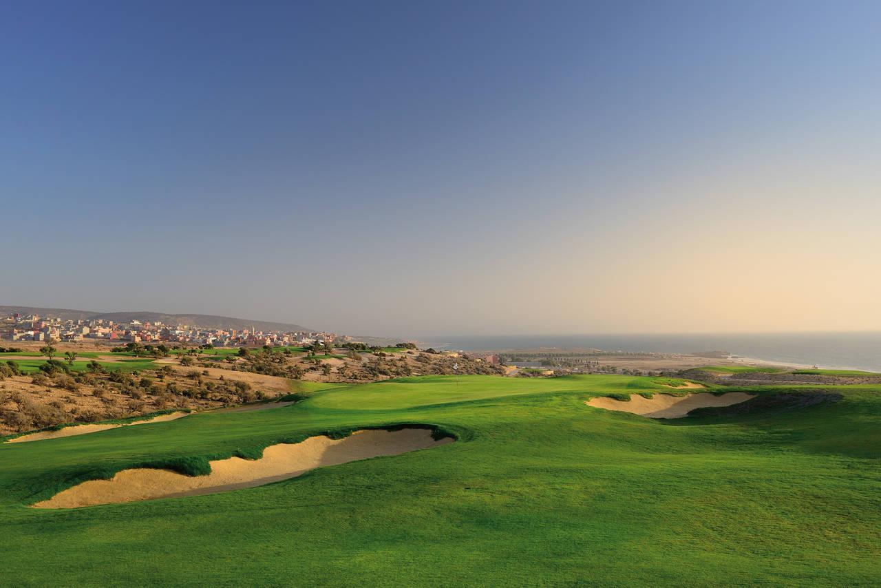 A scenic golf course with ocean and city views and vibrant greens.