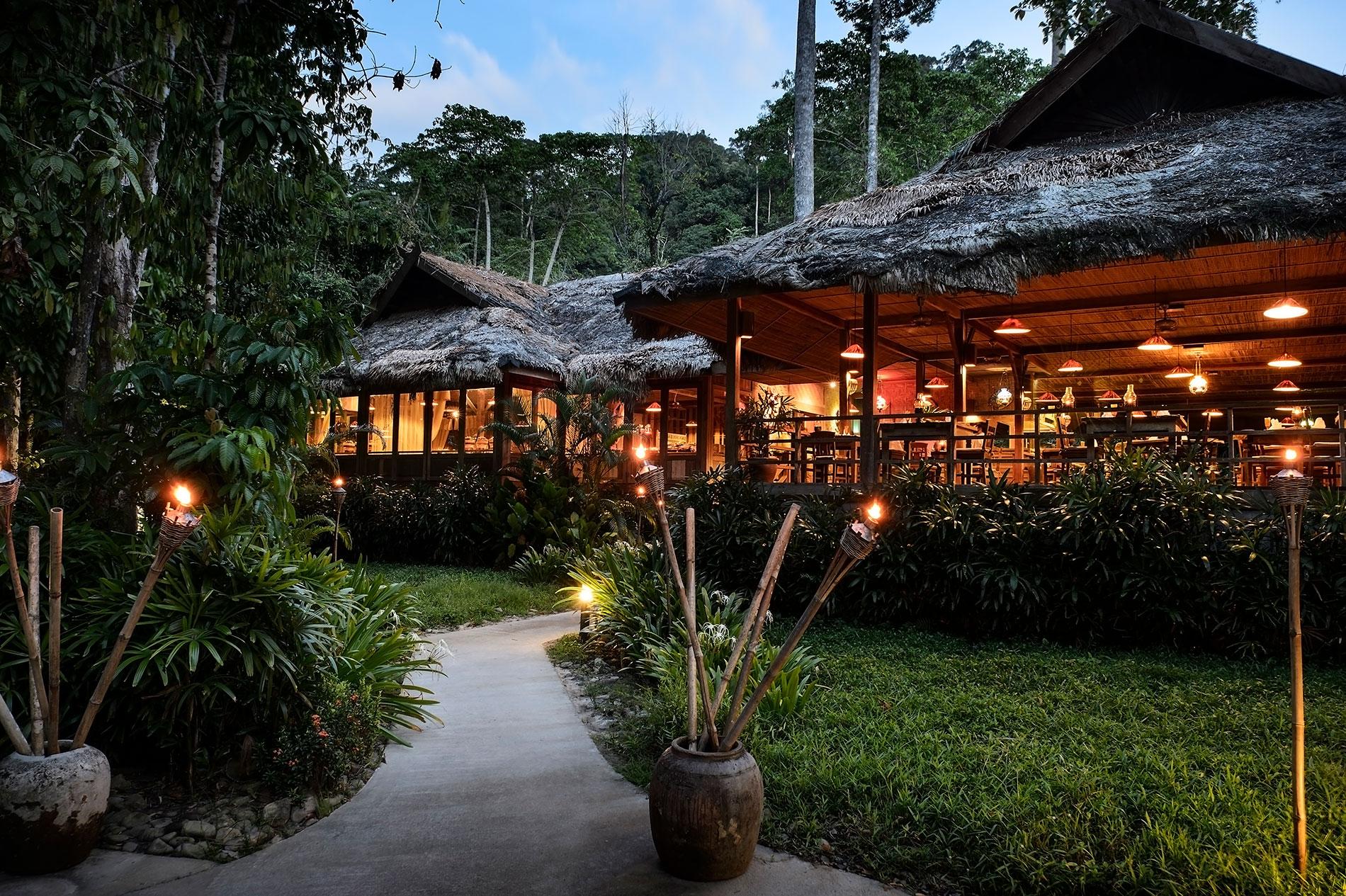 Dining area at The Els Club Teluk Datai under evening light being lit up by lamps