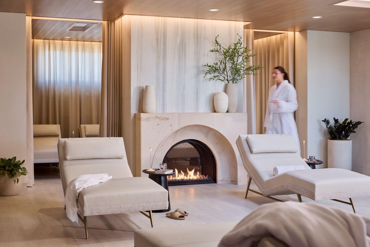 A tranquil spa room with modern loungers, a fireplace, and warm ambient lighting.