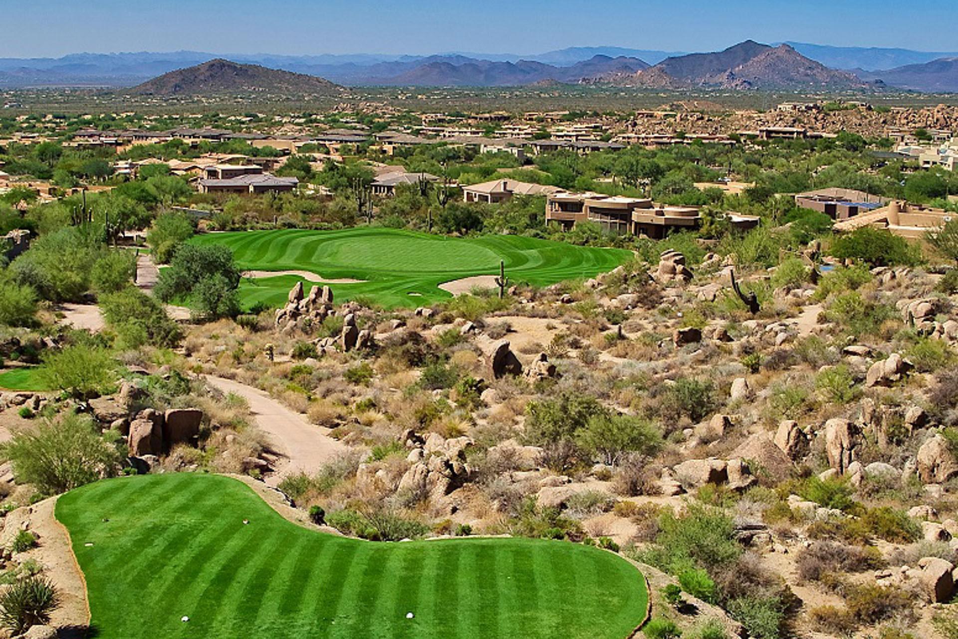 A desert course hole with homes nestled in the surrounding rocky terrain.