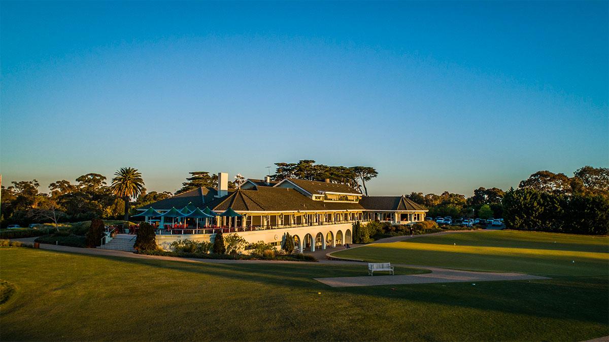 The Victoria Golf Clubhouse overlooking a practice green under clear blue skies