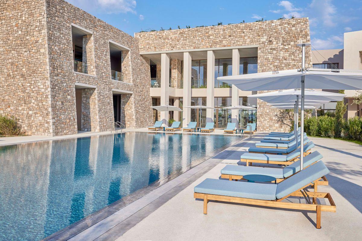 An outdoor swimming pool at the hotel littered with sun beds and umbrellas