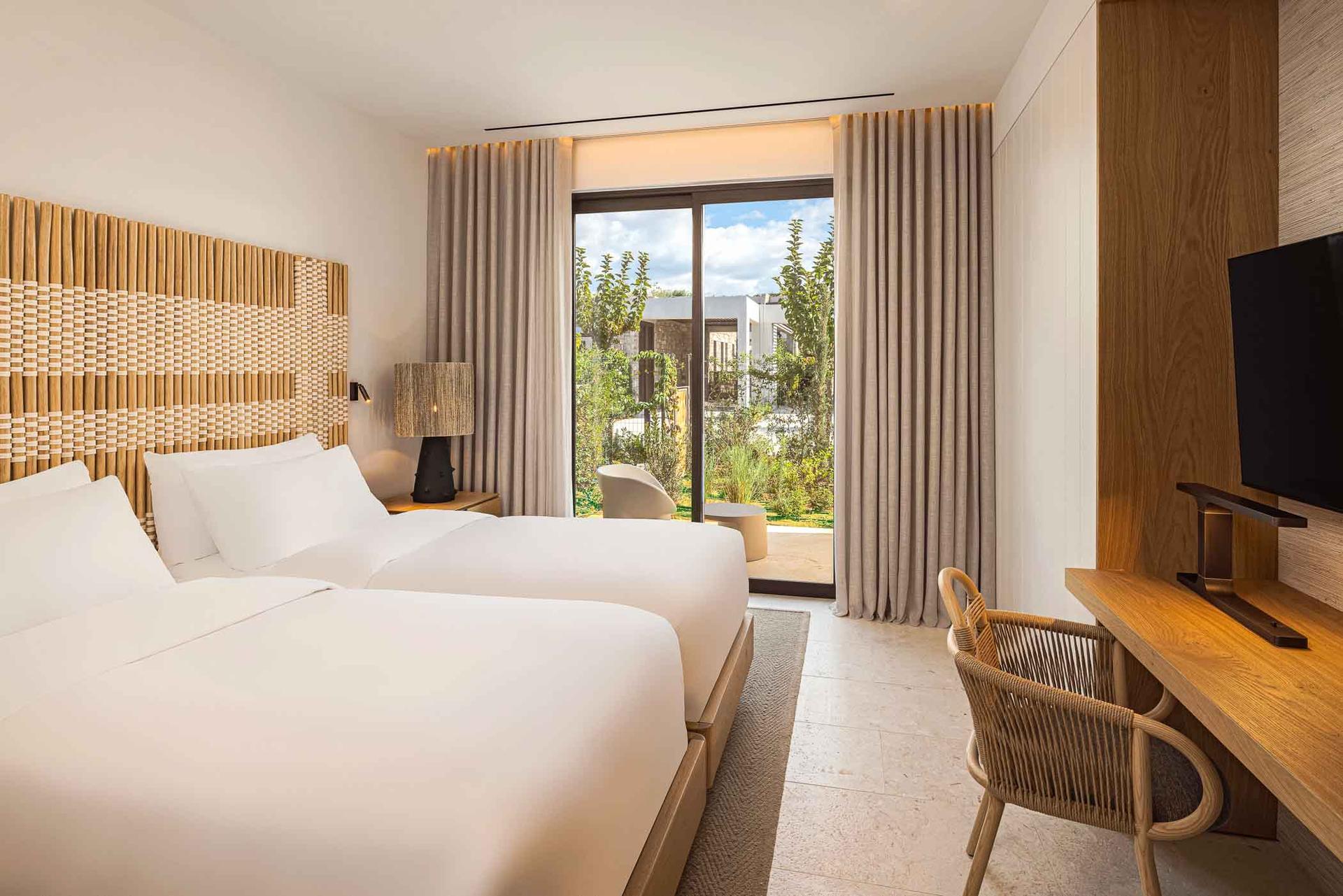 Twin bed room at the hotel following a wooden design and patio