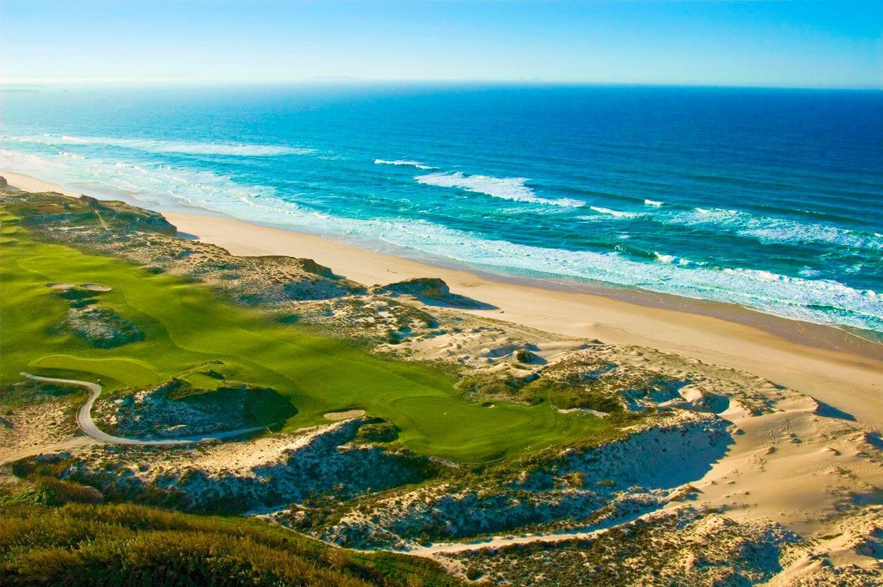 Aerial view of an undulating fairway leading to the green with the beach alongside