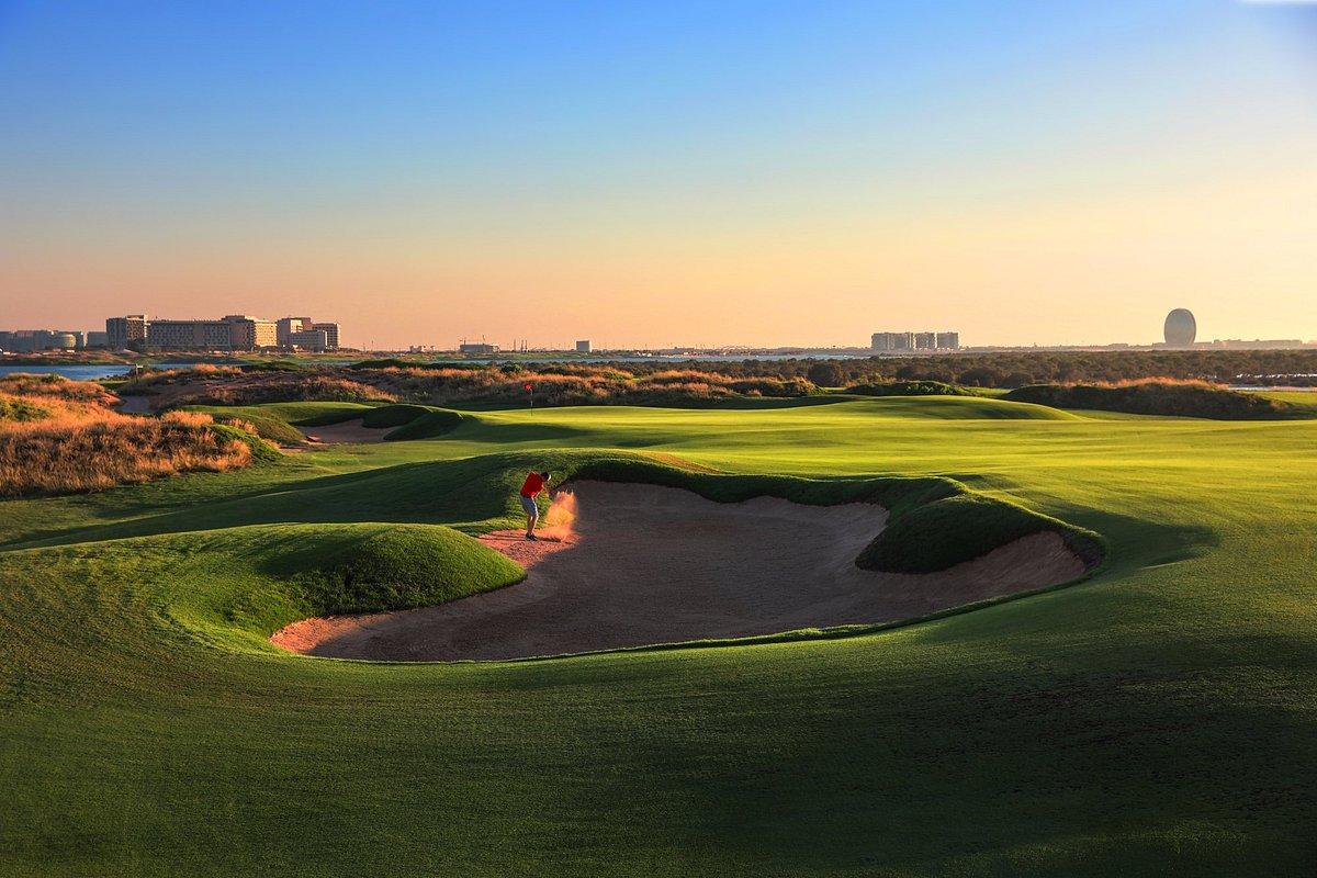 Golfer hitting out of a sand bunker onto a smooth green under the golden sun
