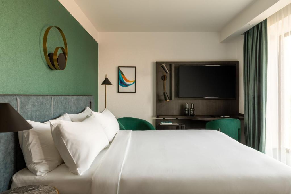 A modern double bed room following a green design with a smart TV