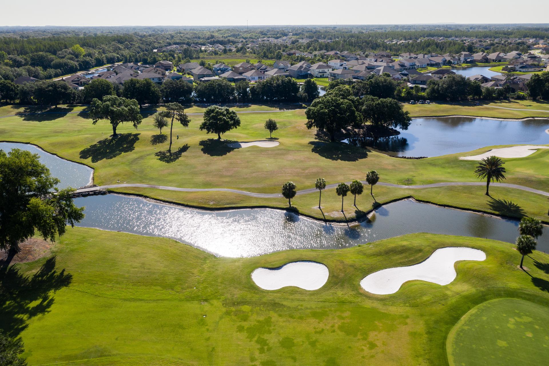 Overhead view of a well maintained fairway nestled with sand bunkers running along a water hazard