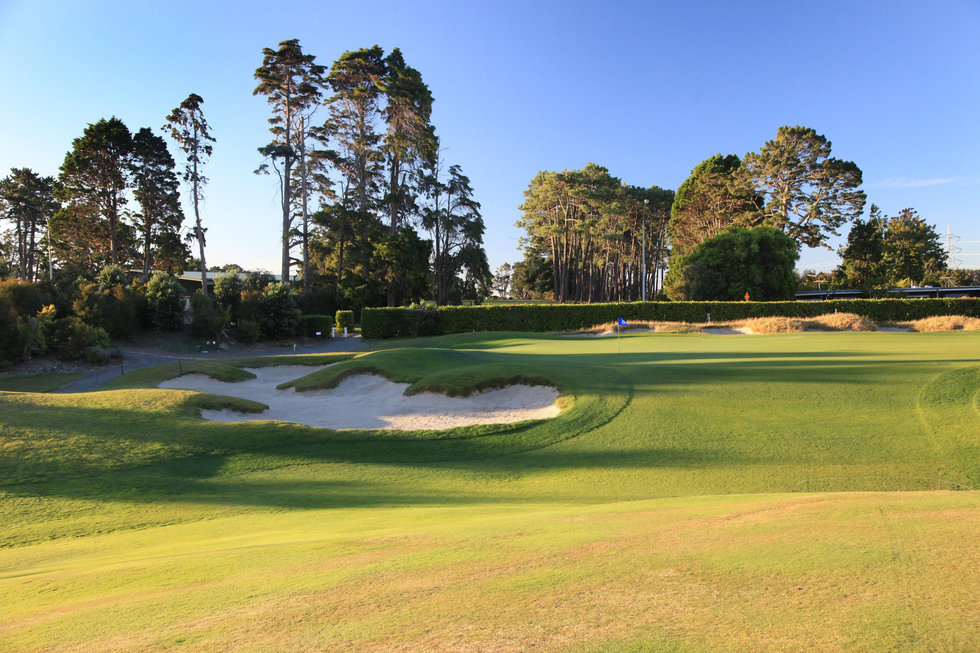 A well maintained fairway with a sand bunker leading towards a smooth green