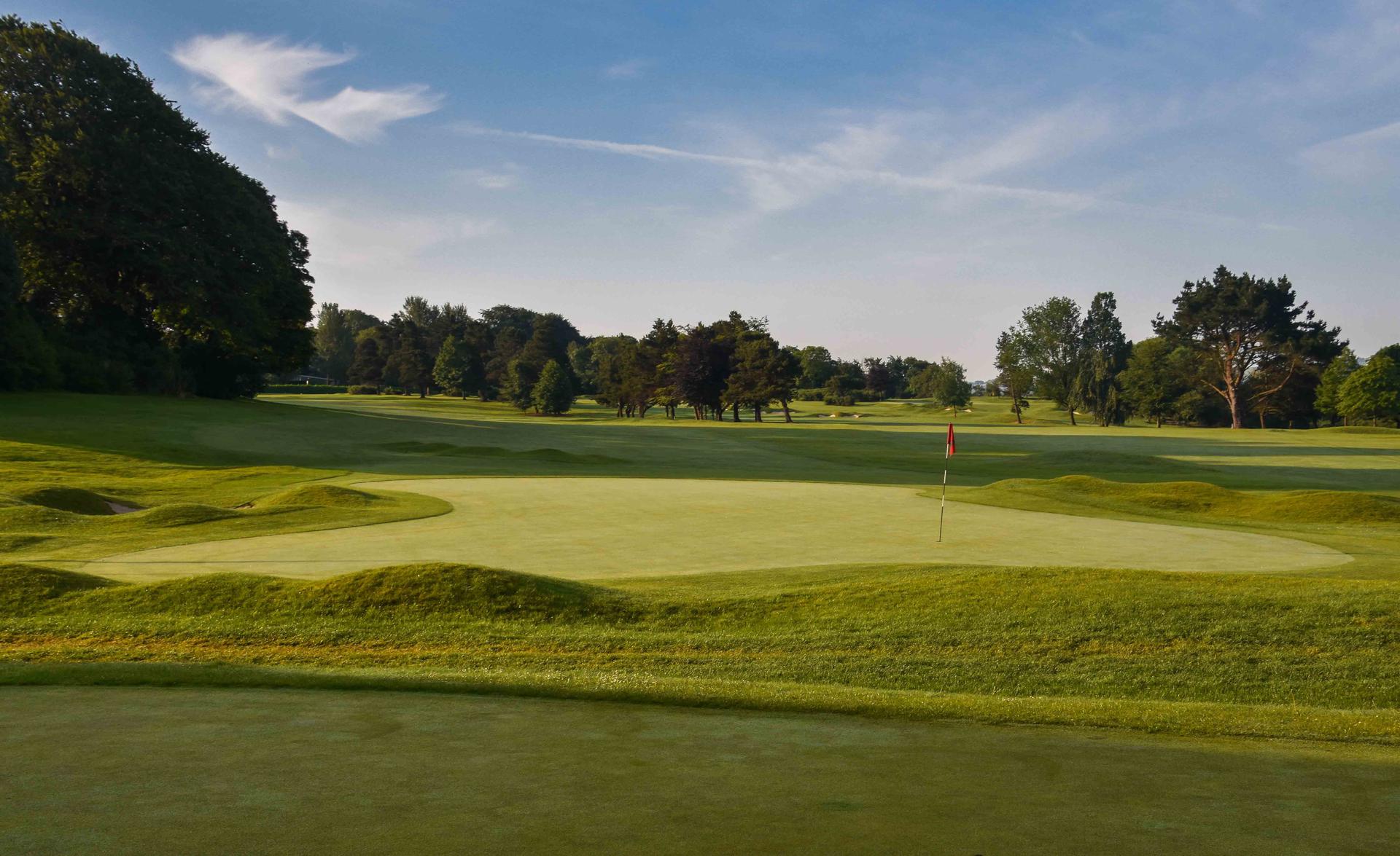Panoramic view of a wide fairway leading to a smooth green surrounded by rolling dunes