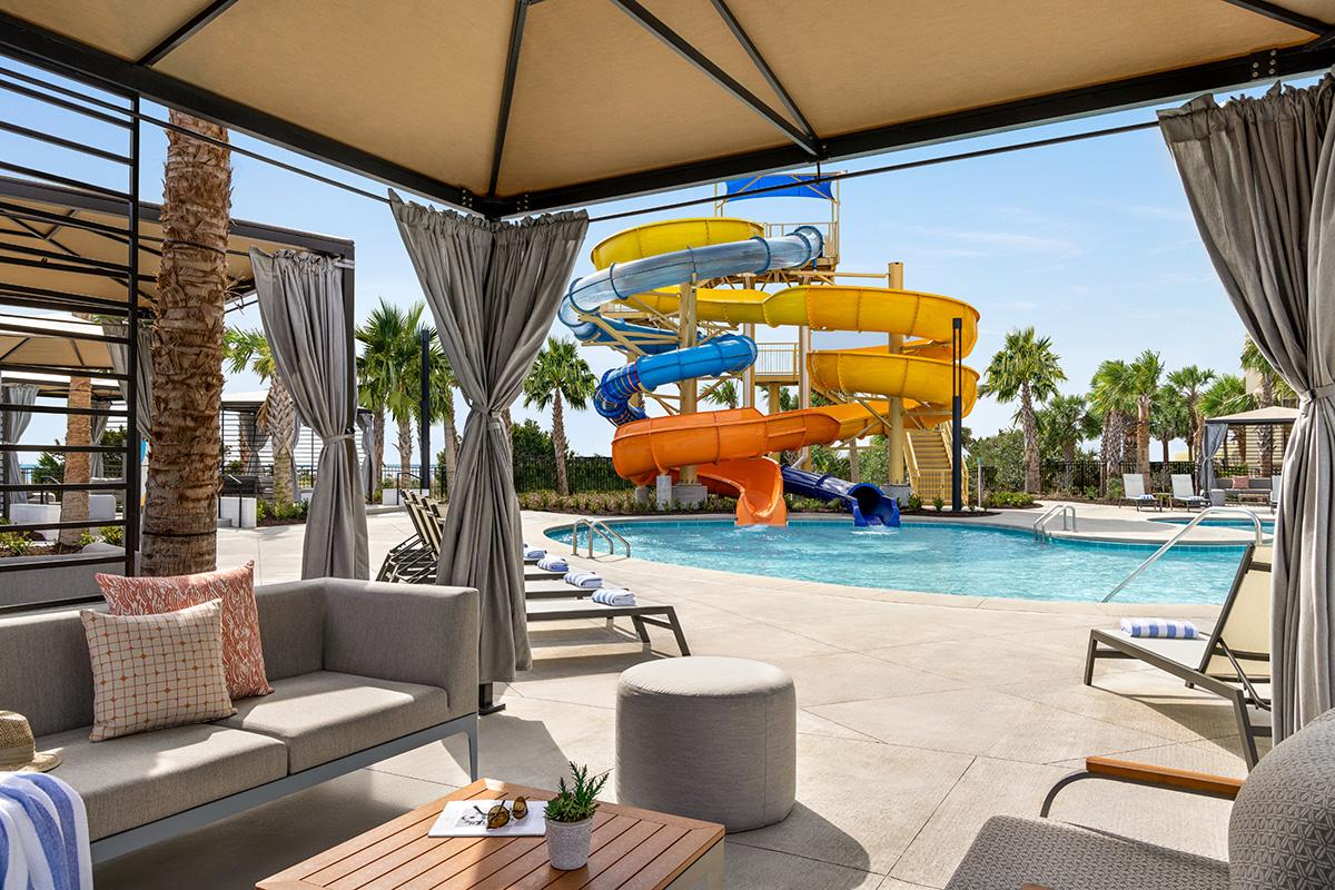 View from a cabana of a water slide leading to an outdoor swimming pool