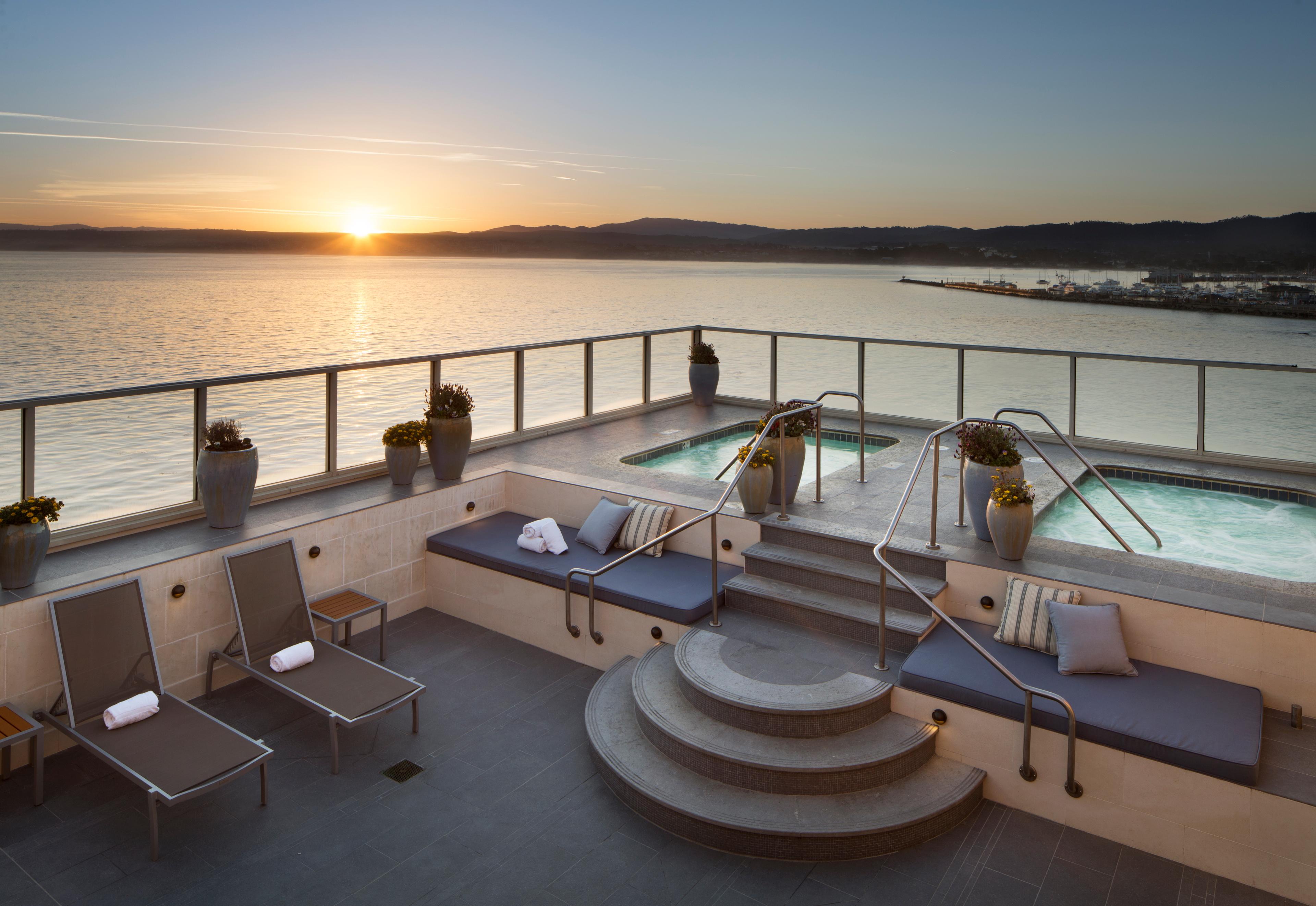 Outdoor jacuzzi with coastal views with the sun setting over the distant mountains