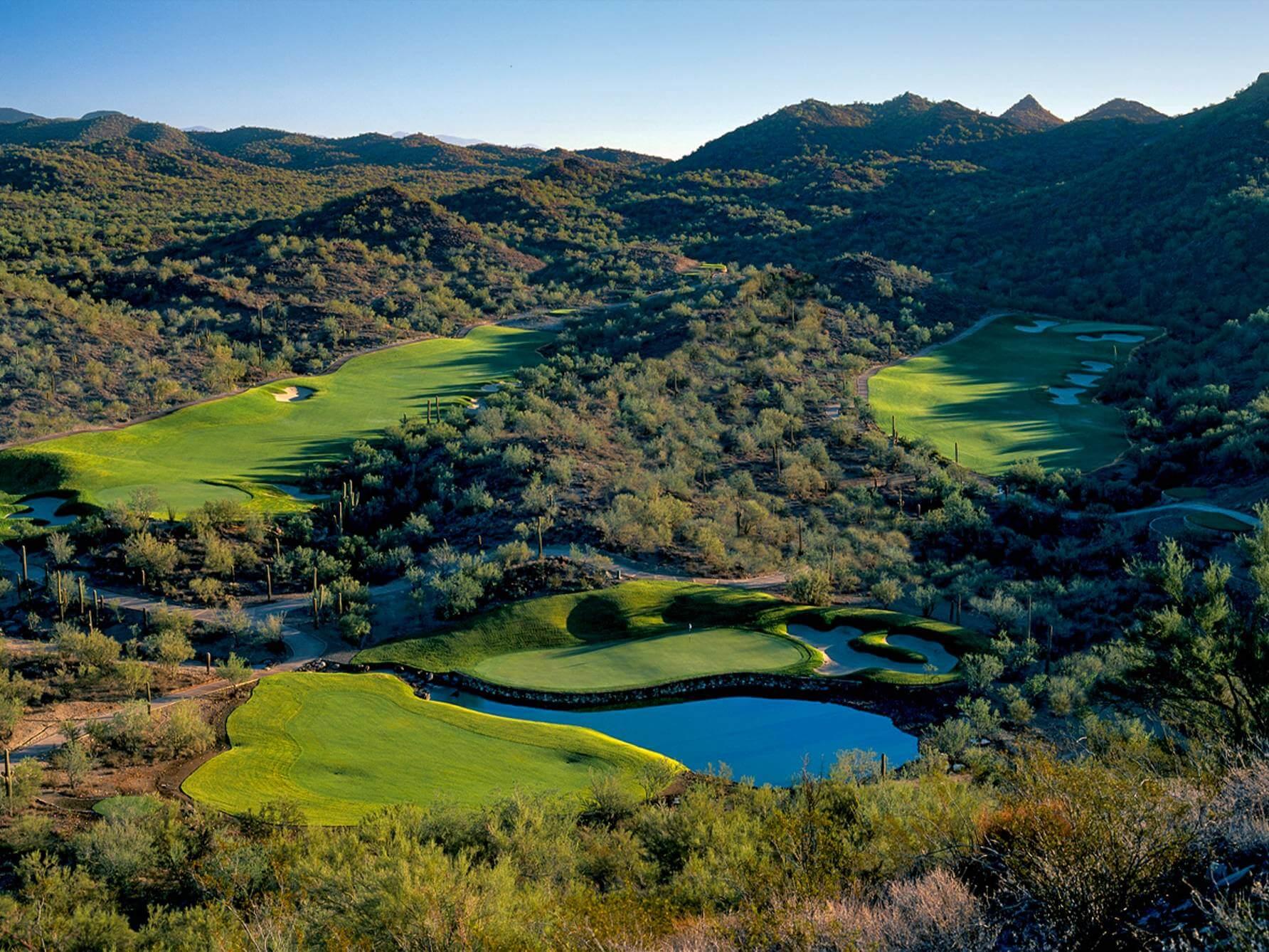 Overhead view of an a green next to a water hazard surrounded by a rough