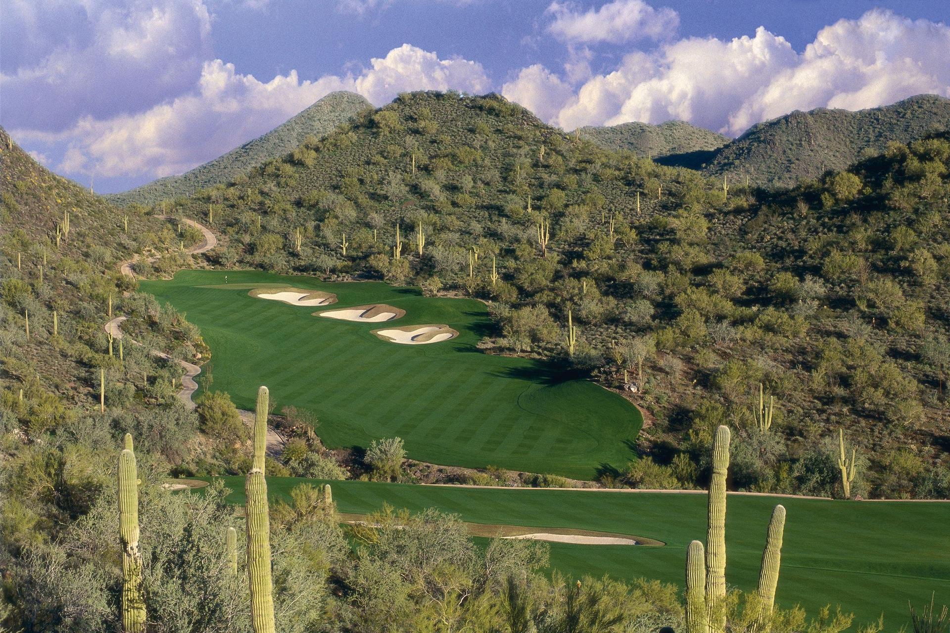 A wide fairway nestled with sand bunkers leading down hill