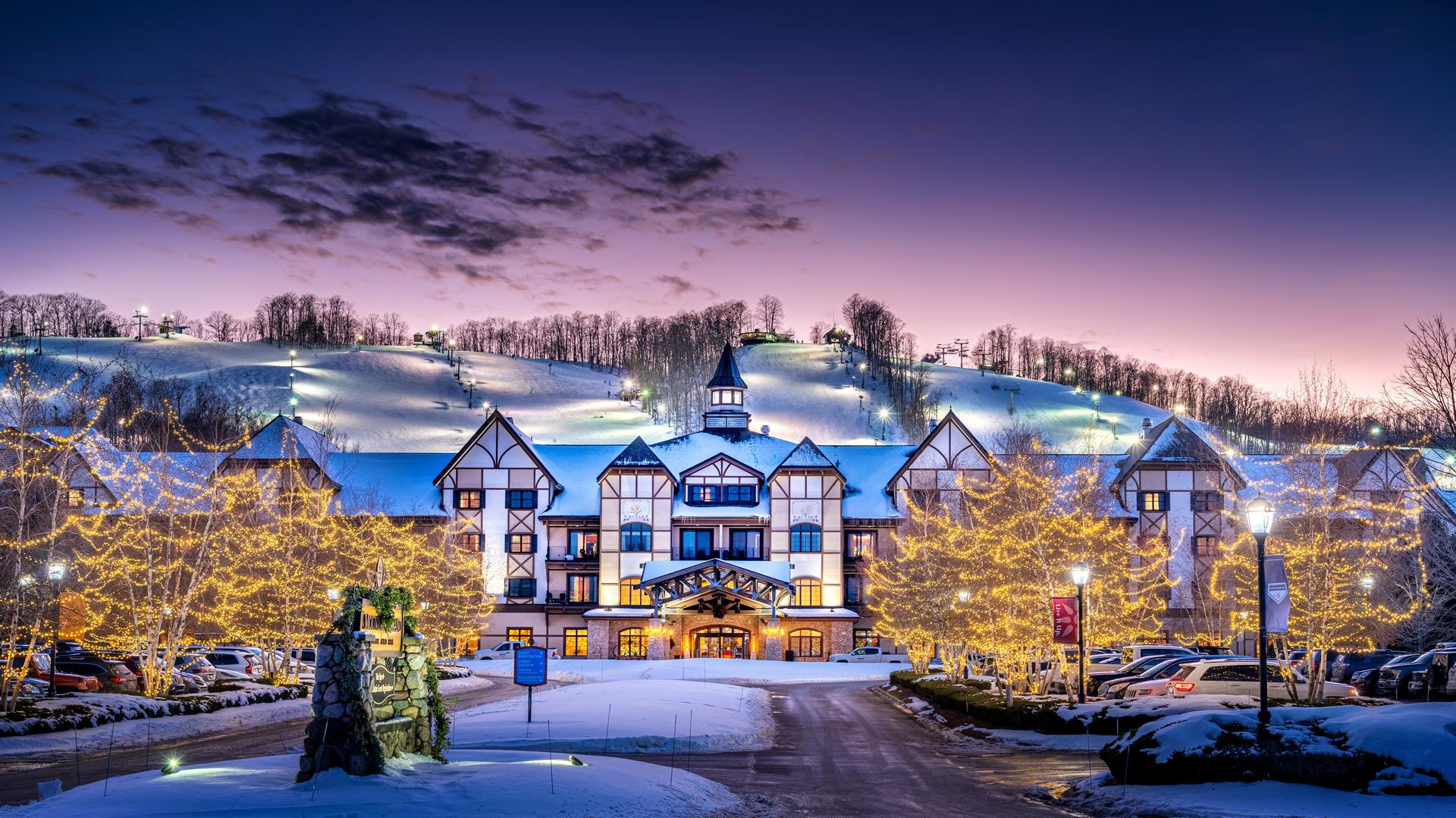 Exterior view of the Boyne Mountain Resort during snow season with Christmas lights in the trees