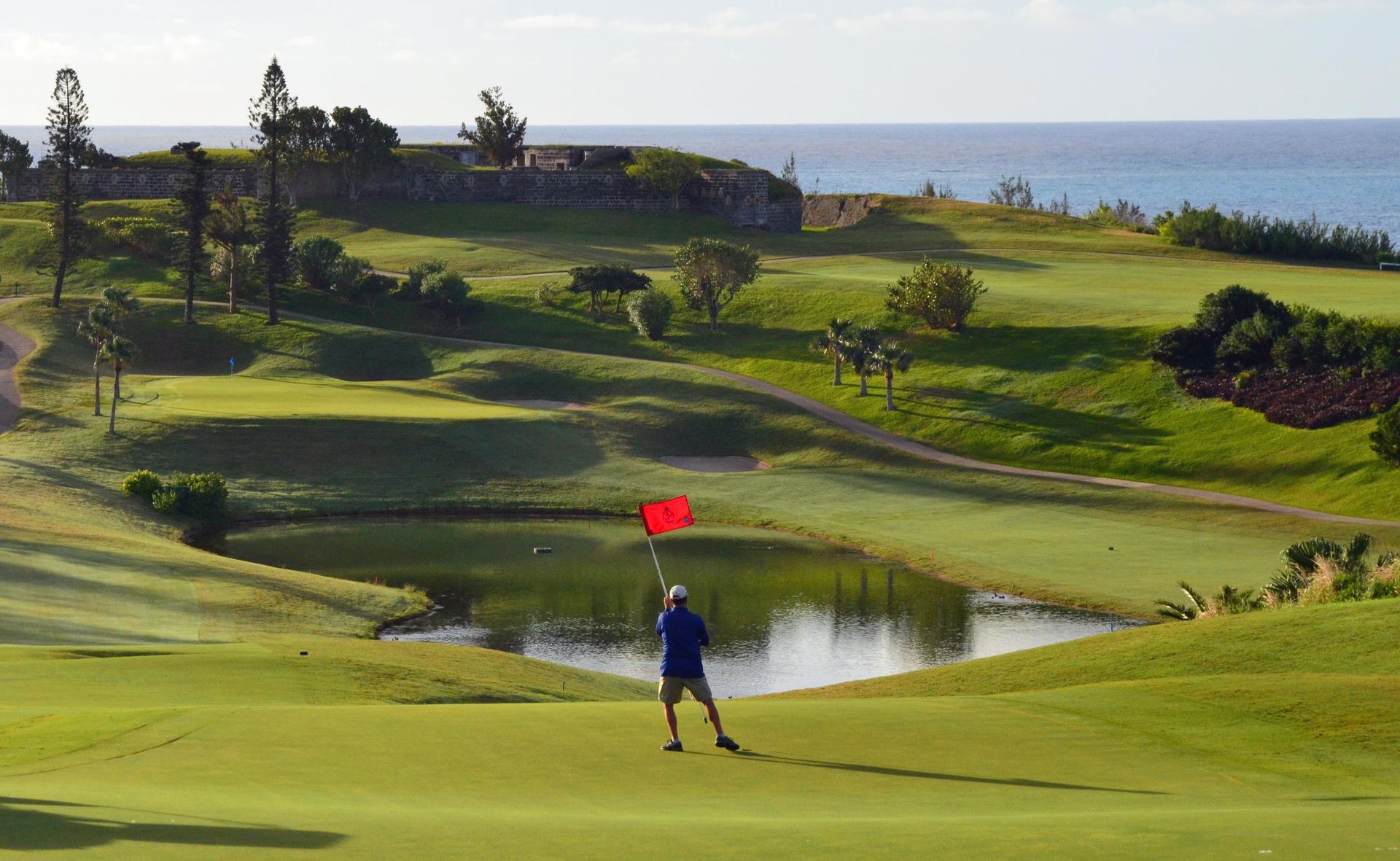 A man taking a red flagstick out of the hole at the Port Royal GC