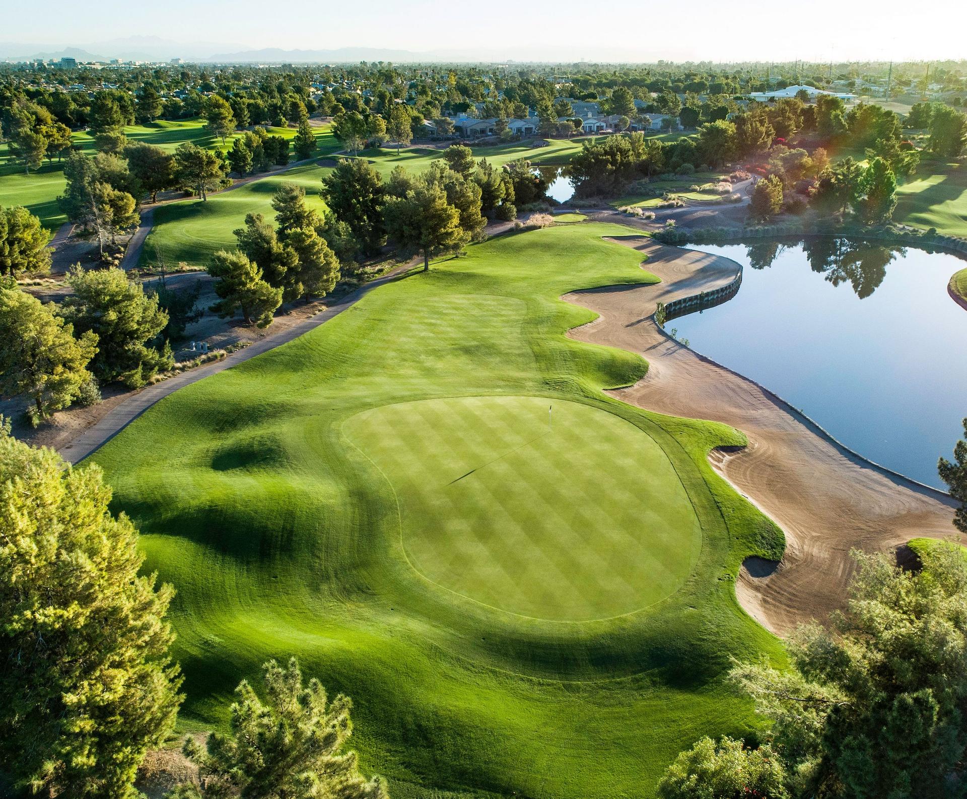 Overhead view of a manicured green next to a sand bunker and water hazard