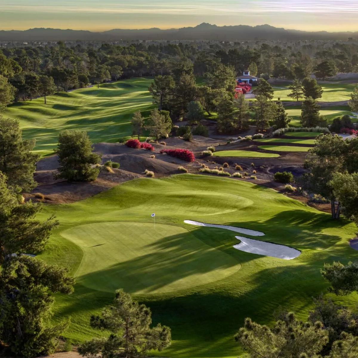 Overhead view of an elevated green next to a sand bunker with mountain views in the distance