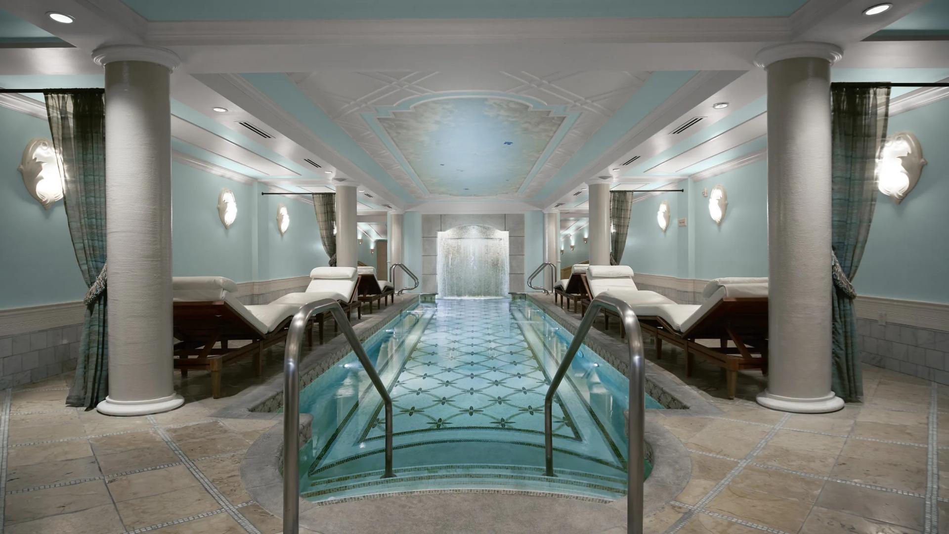Panoramic view of a indoor swimming pool surrounded by sunbeds